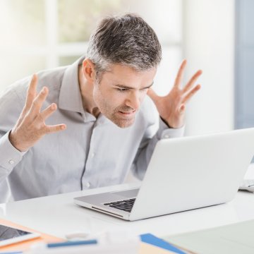 Advanced System Optimizer software system optimizer utility software overview benefits angry man frustrated annoyed in front of white laptop in office